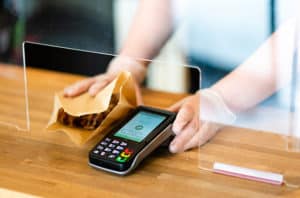 Person handing a pastry and payment processing terminal to a customer