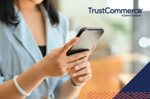 Photo of a woman holding a cell phone with TrustCommerce logo in the right corner.