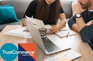 Image of a couple looking at medical bills on a table with the TrustCommerce logo in the corner.